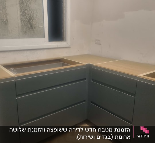 ארונות מטבח חדשים בפינת חדר עם רצפת עץ